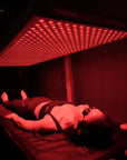 Person in a dark room with red light therapy panel