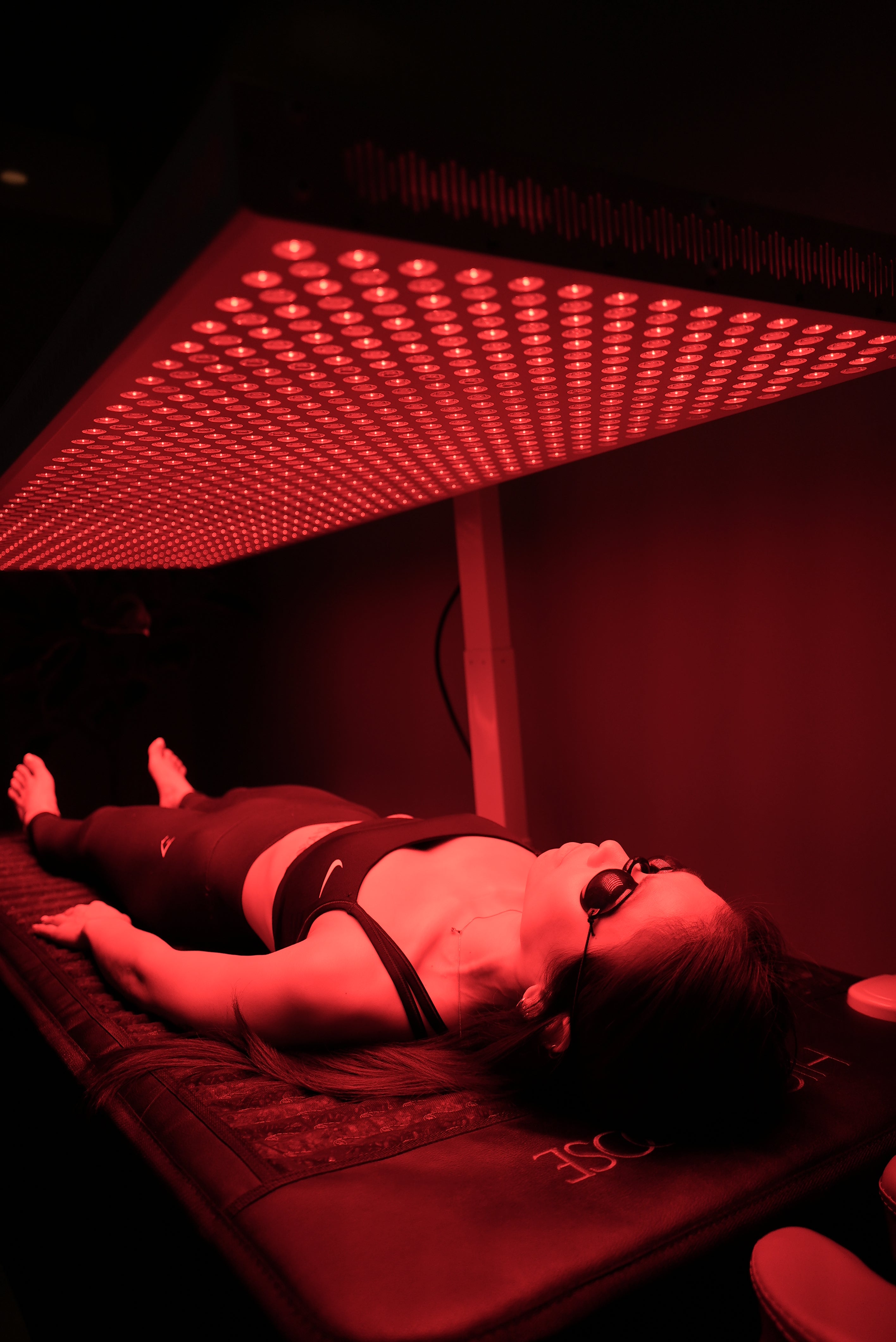 Person in a dark room with red light therapy panel